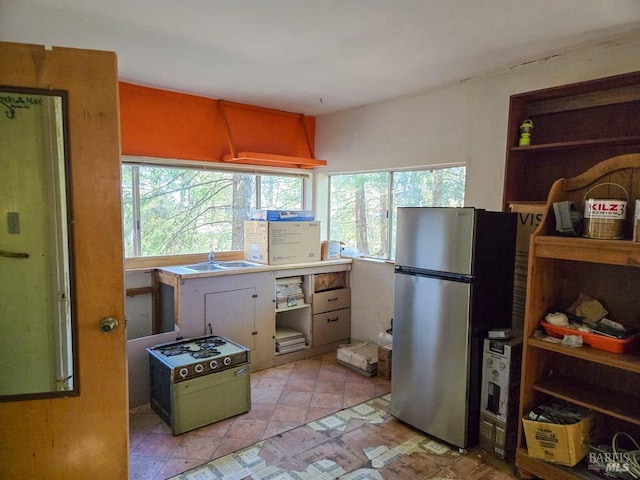 kitchen featuring gas range, open shelves, and freestanding refrigerator