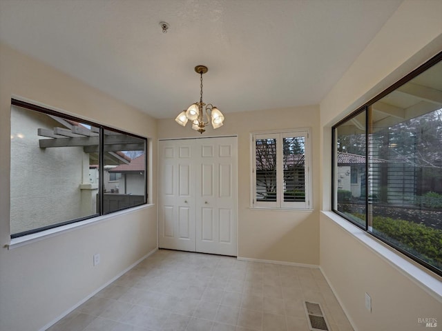 unfurnished dining area featuring a chandelier, visible vents, and baseboards