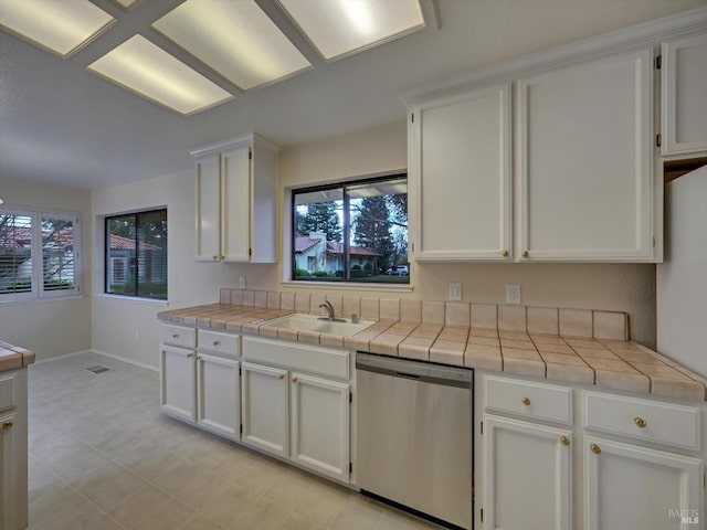 kitchen with white cabinetry, visible vents, dishwasher, a sink, and tile counters