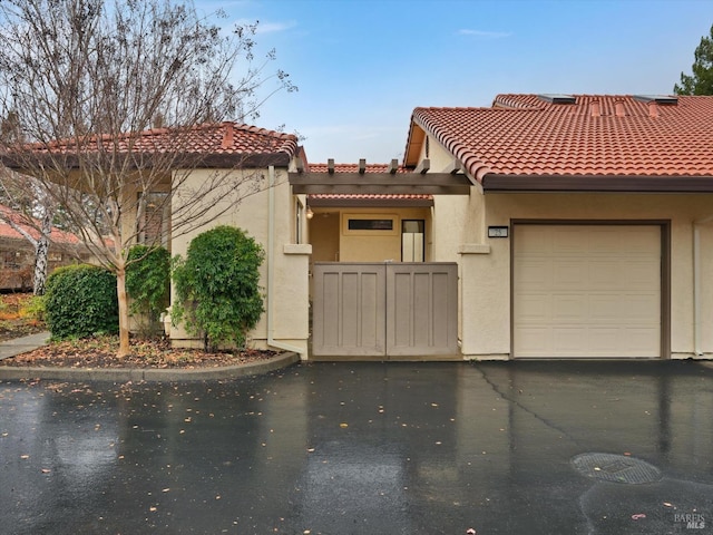 view of front of property featuring driveway, stucco siding, an attached garage, and a tile roof