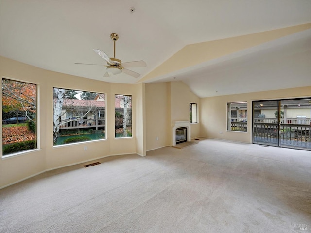 unfurnished living room with visible vents, a ceiling fan, carpet, a glass covered fireplace, and lofted ceiling