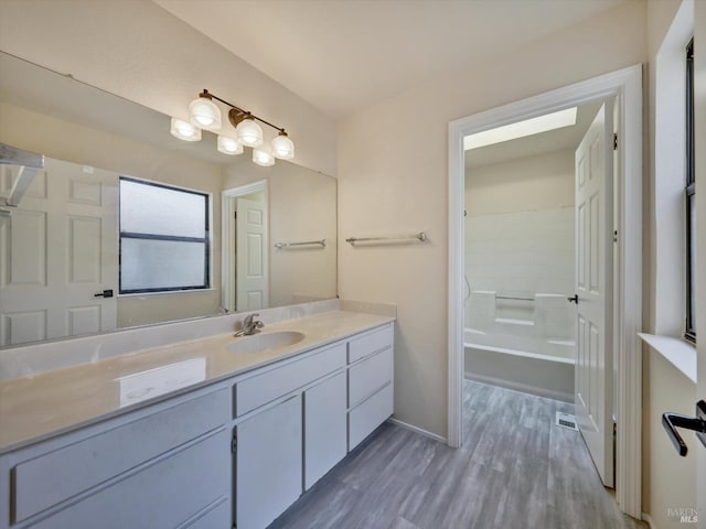 bathroom featuring vanity, baseboards, shower / tub combination, visible vents, and wood finished floors