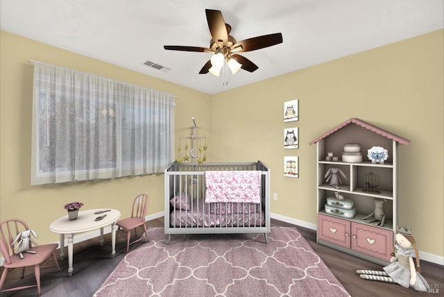 bedroom with hardwood / wood-style flooring, ceiling fan, and a crib