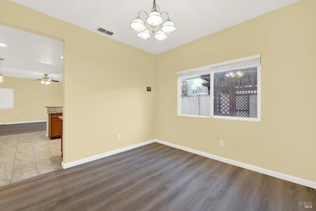 spare room with ceiling fan with notable chandelier and light hardwood / wood-style floors