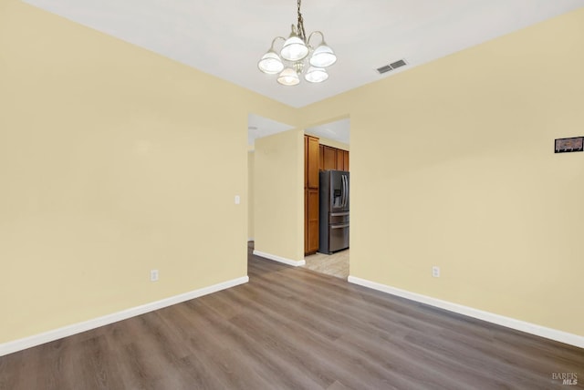 empty room with an inviting chandelier and light hardwood / wood-style flooring