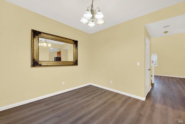 empty room with wood-type flooring and an inviting chandelier