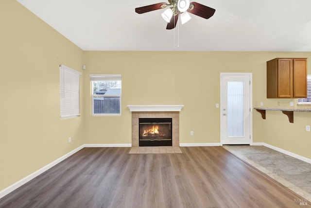 unfurnished living room with ceiling fan, a fireplace, and light wood-type flooring