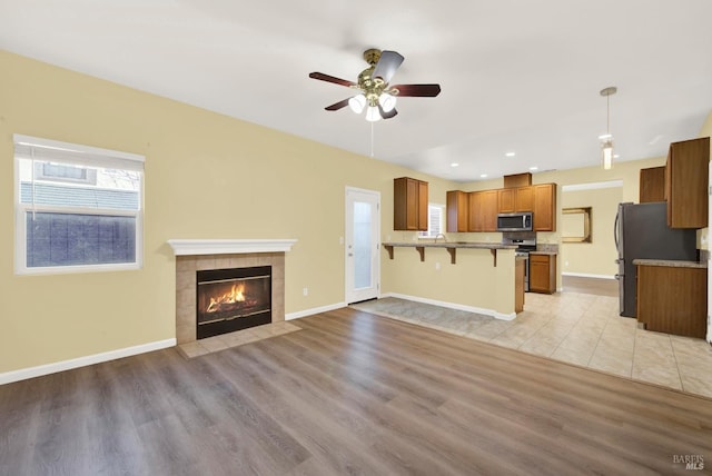 kitchen with kitchen peninsula, pendant lighting, light hardwood / wood-style floors, a breakfast bar, and appliances with stainless steel finishes