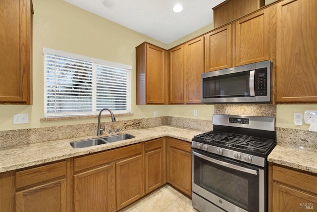 kitchen with light stone countertops, sink, and appliances with stainless steel finishes