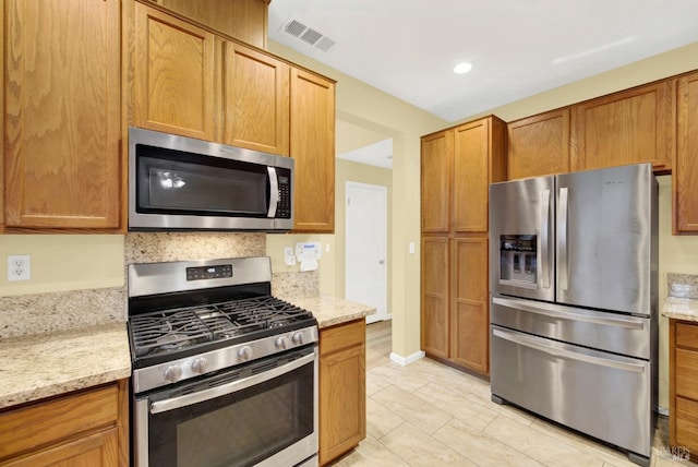 kitchen featuring light stone countertops, light tile patterned floors, and stainless steel appliances