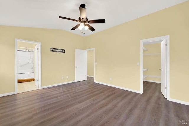 unfurnished bedroom featuring a walk in closet, ensuite bathroom, ceiling fan, wood-type flooring, and a closet