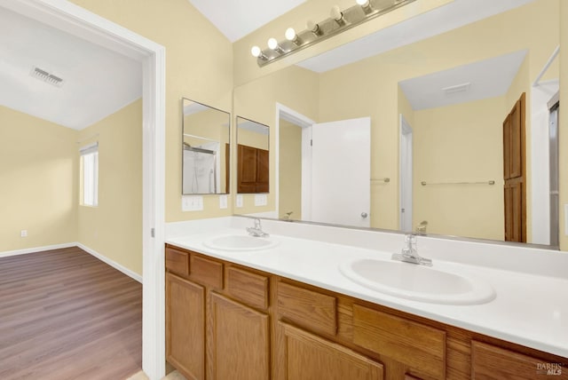 bathroom with vanity, hardwood / wood-style flooring, and vaulted ceiling