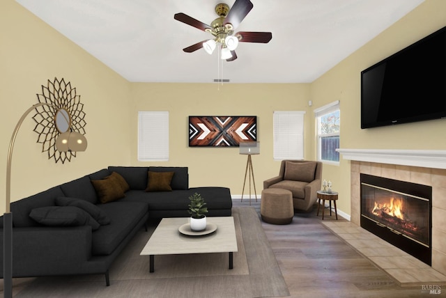 living room featuring a fireplace, ceiling fan, and light hardwood / wood-style flooring