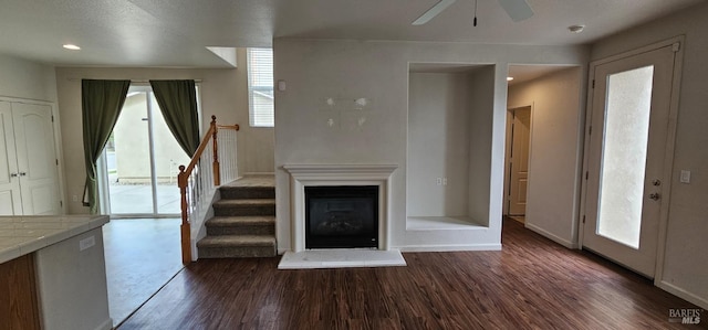 unfurnished living room with ceiling fan, dark hardwood / wood-style flooring, and a textured ceiling