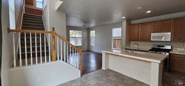 kitchen featuring sink, hardwood / wood-style flooring, ceiling fan, tile counters, and stainless steel range oven