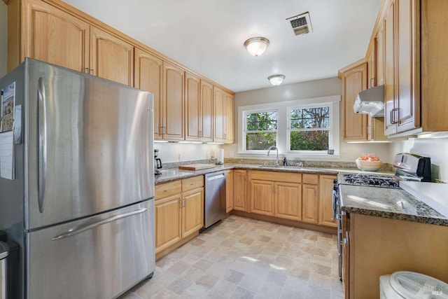 kitchen with dark stone countertops, light brown cabinetry, sink, and appliances with stainless steel finishes