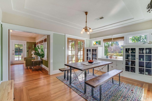 dining area with a chandelier, french doors, a healthy amount of sunlight, and light hardwood / wood-style flooring