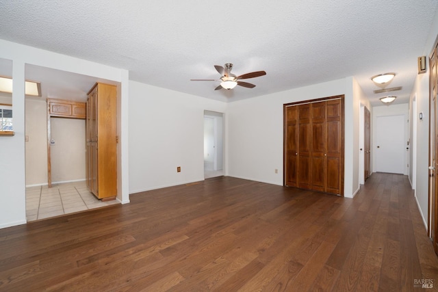 unfurnished bedroom with a textured ceiling, a closet, wood finished floors, and baseboards