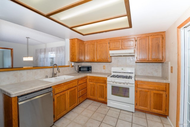 kitchen with stainless steel appliances, backsplash, a sink, and under cabinet range hood