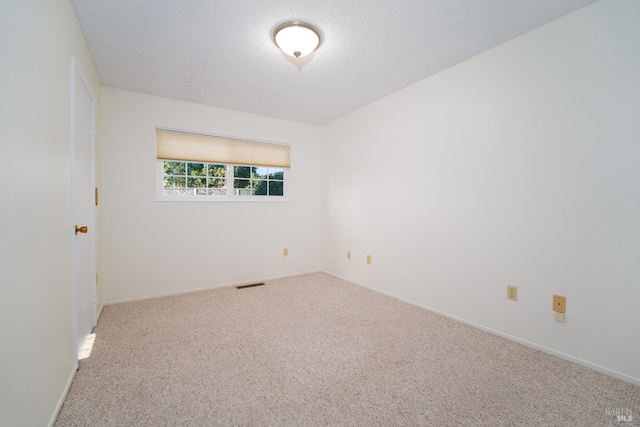 carpeted spare room featuring a textured ceiling, visible vents, and baseboards