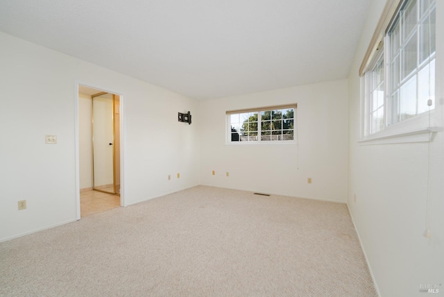 spare room featuring light colored carpet and visible vents