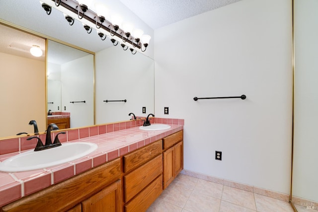 bathroom with double vanity, tile patterned flooring, a textured ceiling, and a sink