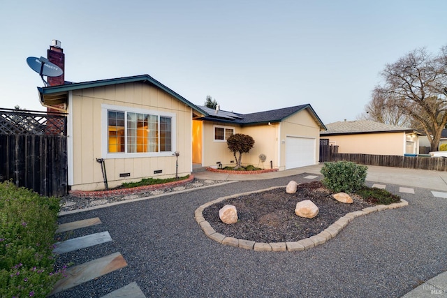 ranch-style house with driveway, crawl space, an attached garage, fence, and roof mounted solar panels