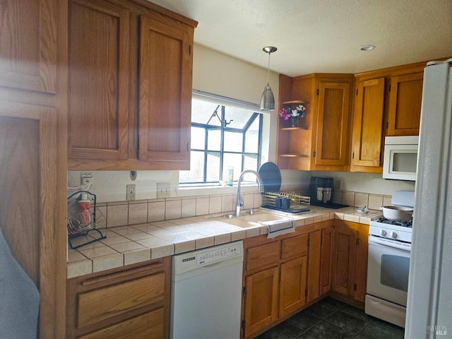 kitchen featuring tile counters, sink, dark tile patterned floors, pendant lighting, and white appliances