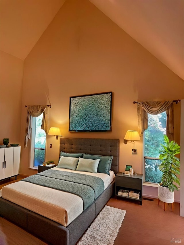 carpeted bedroom with high vaulted ceiling and multiple windows