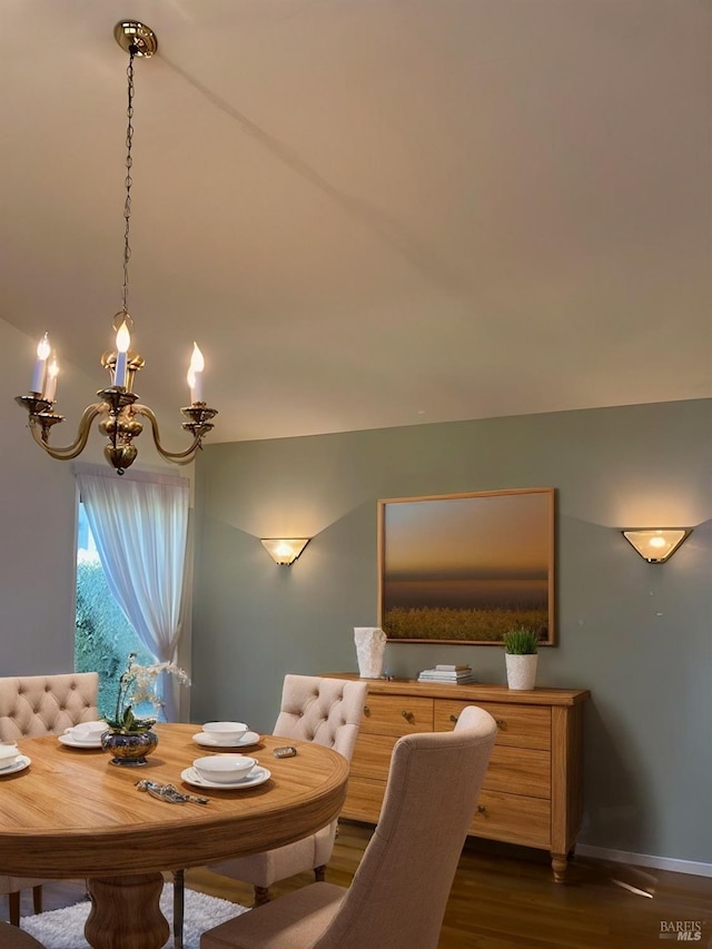 dining space with dark wood-type flooring and an inviting chandelier