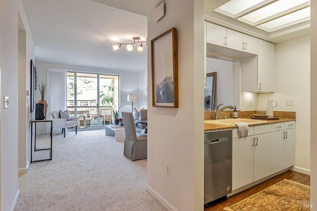 kitchen featuring white cabinets, dishwasher, sink, and light carpet