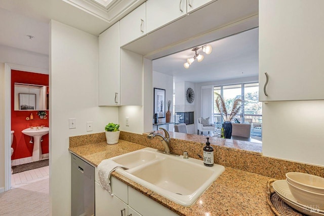 kitchen featuring light stone countertops, sink, light tile patterned floors, dishwasher, and white cabinetry