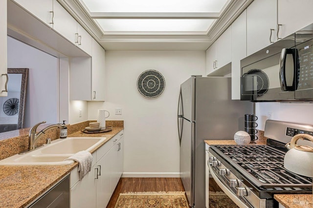 kitchen featuring white cabinets, stainless steel gas stove, light stone counters, and sink