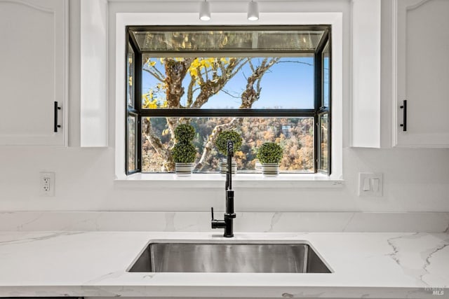 kitchen featuring white cabinets, light stone countertops, plenty of natural light, and sink