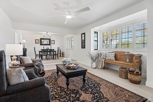 living room with ceiling fan with notable chandelier