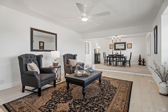 living room featuring ceiling fan with notable chandelier and light hardwood / wood-style floors