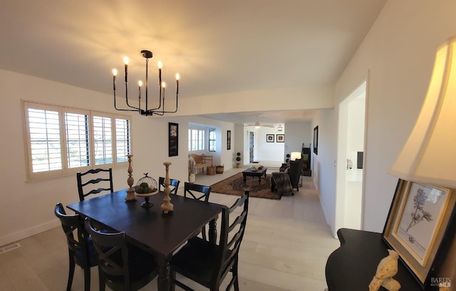 dining room with ceiling fan with notable chandelier and light hardwood / wood-style floors