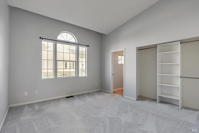 unfurnished bedroom featuring light colored carpet, a closet, and lofted ceiling