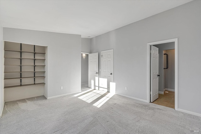 unfurnished bedroom featuring light carpet and ensuite bath