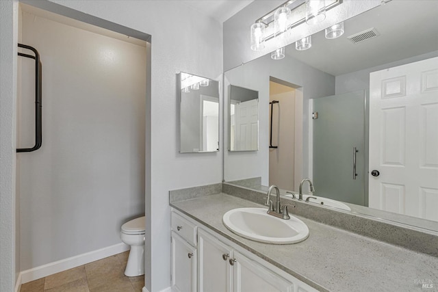 bathroom featuring toilet, vanity, tile patterned floors, and a shower with door