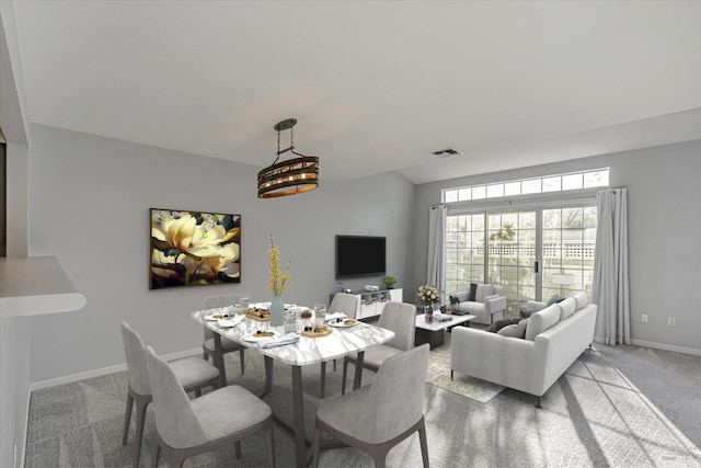 carpeted dining area featuring a notable chandelier