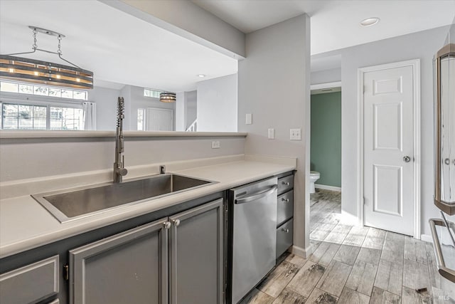 kitchen with dishwasher, gray cabinets, light wood-type flooring, and sink