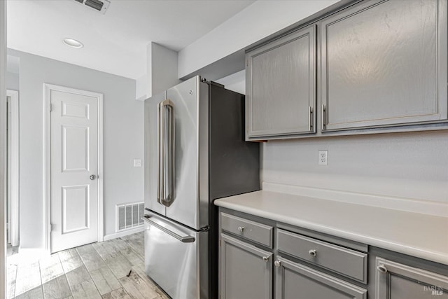 kitchen with gray cabinets, stainless steel fridge, and light hardwood / wood-style floors