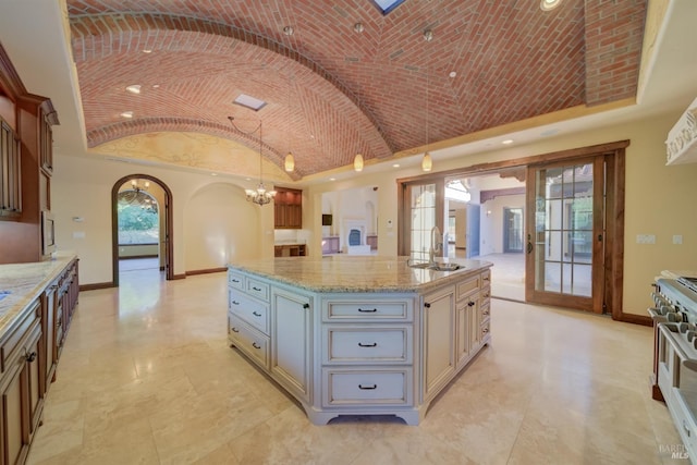 kitchen with a center island, french doors, sink, vaulted ceiling, and decorative light fixtures