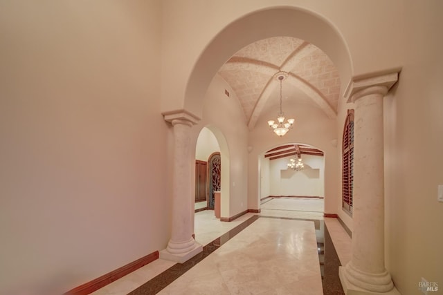 hall with decorative columns, light tile patterned floors, a chandelier, and vaulted ceiling