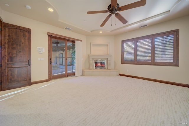 unfurnished living room with carpet flooring, ceiling fan, and a tray ceiling