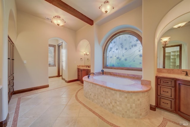 bathroom featuring beamed ceiling, vanity, tile patterned floors, and tiled tub