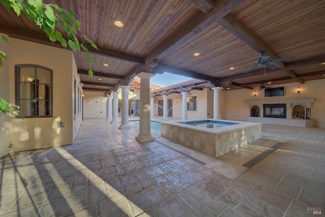 view of patio with ceiling fan, a pool with hot tub, and exterior fireplace