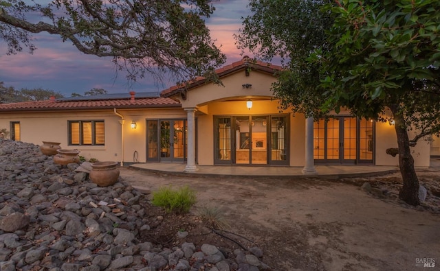 back house at dusk with a patio area