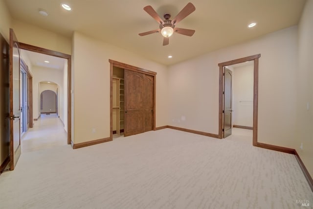 unfurnished bedroom with ceiling fan, light carpet, and a closet